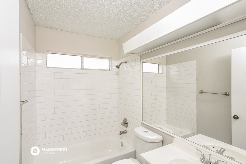 a white bathroom with a tub and a sink and a mirror