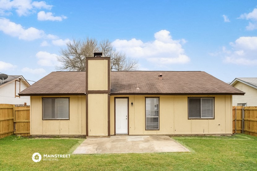 the front of a yellow house with a yard and a white door
