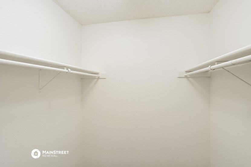 a walk in closet with white walls and two white rods on the wall and two