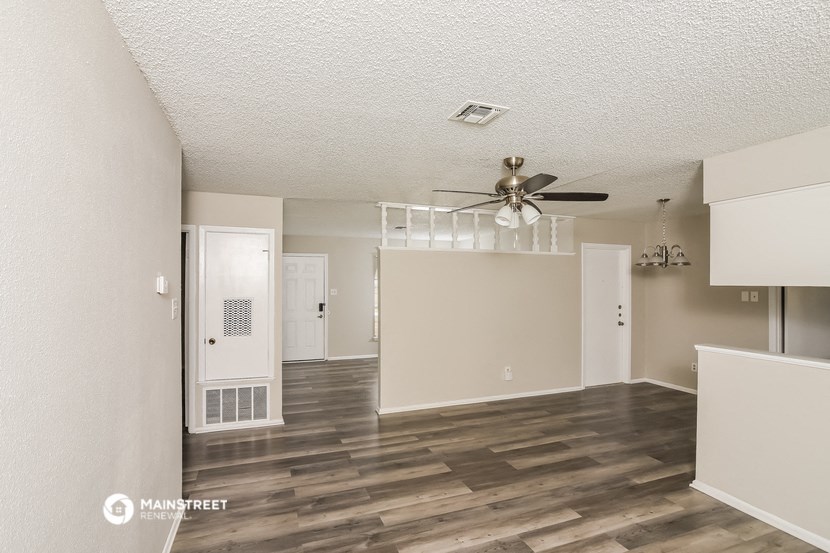 an empty living room with a ceiling fan