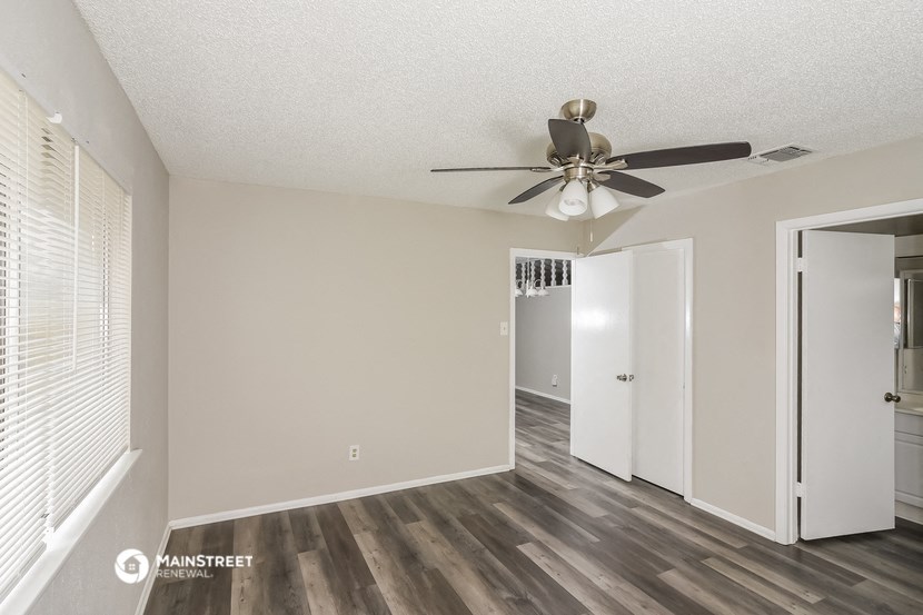 an empty living room with a ceiling fan and a closet