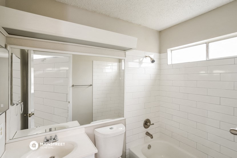 a white bathroom with a tub and a sink and a mirror