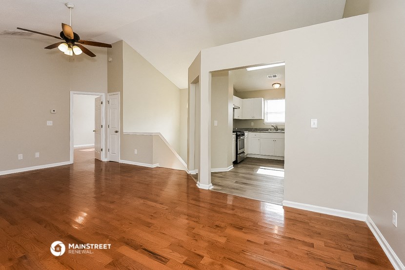 an empty living room with wood floors and a ceiling fan