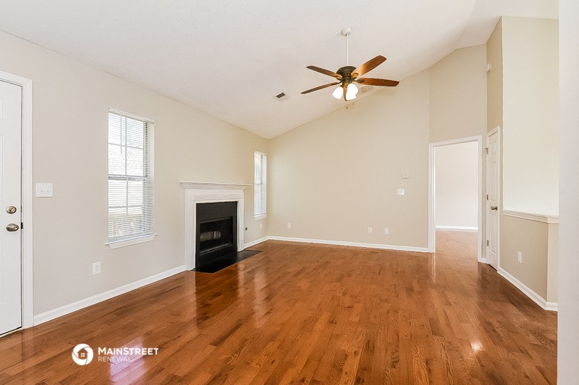 an empty living room with a fireplace and a ceiling fan