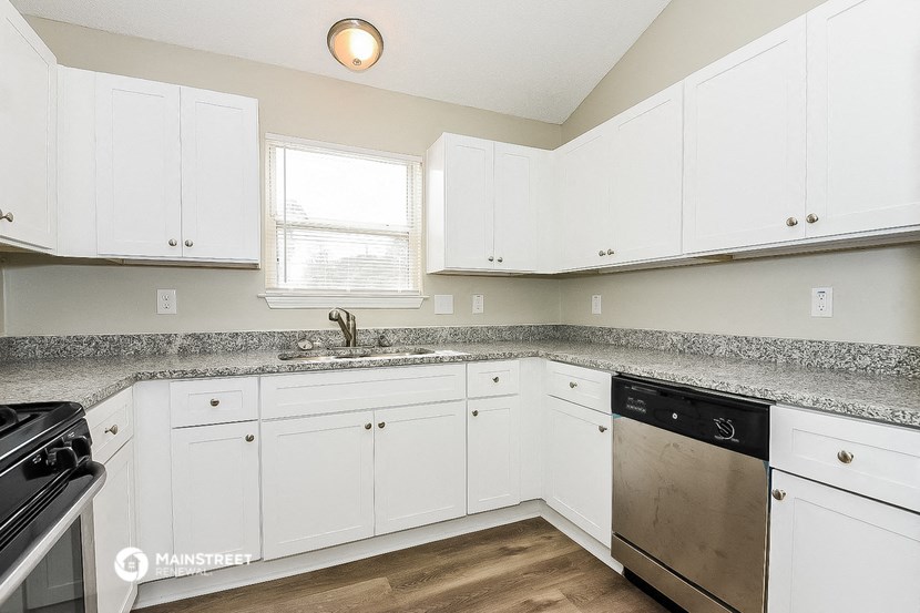 a kitchen with white cabinets and granite counter tops