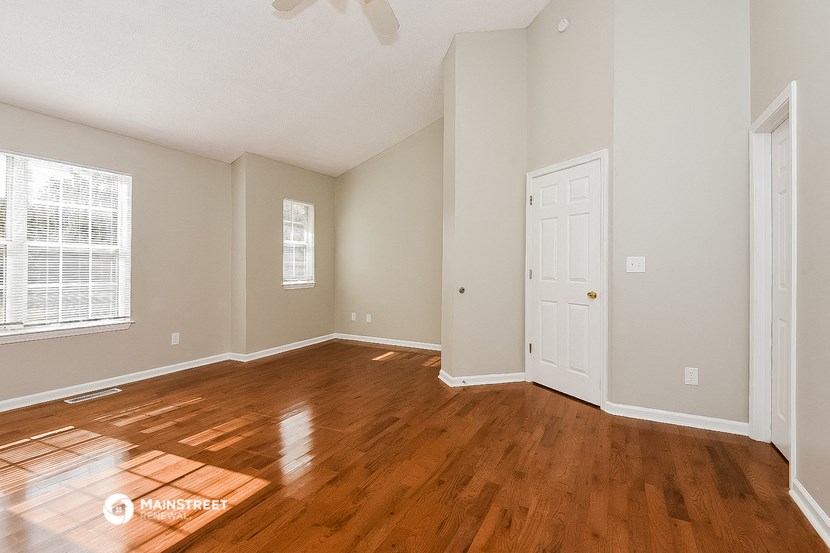 the living room of an empty house with wooden floors and a white door