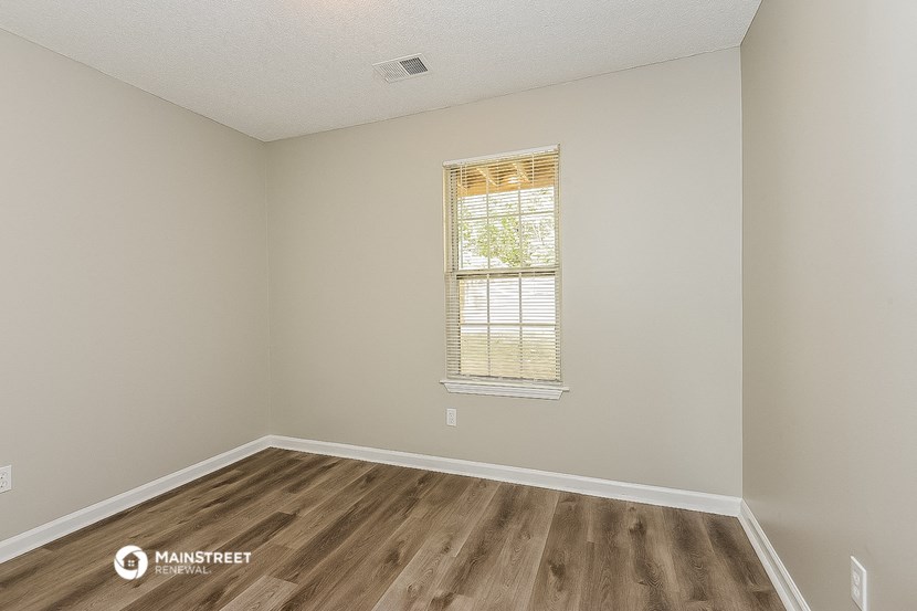 an empty room with wooden floors and a window