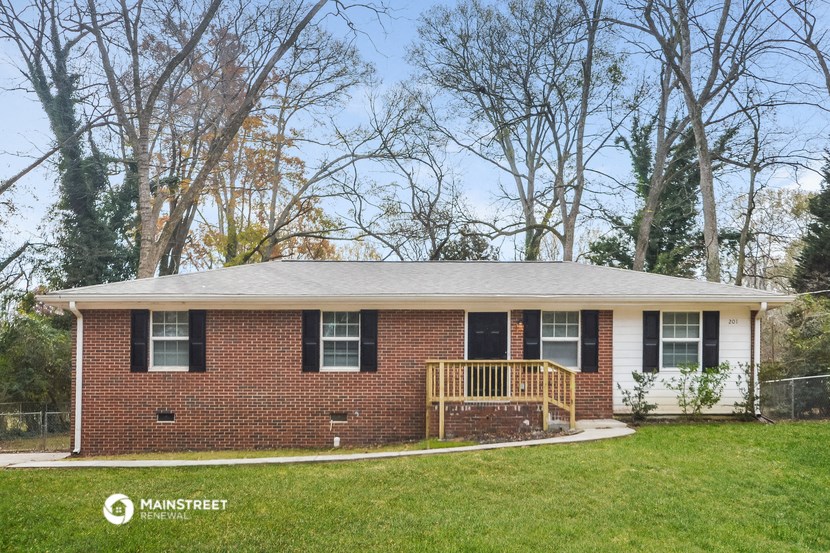 a small brick house with a porch and a lawn