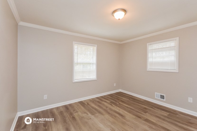 the spacious living room with hardwood flooring and two windows
