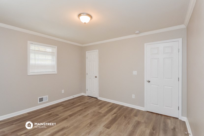 the living room of a house with a wooden floor and a white door
