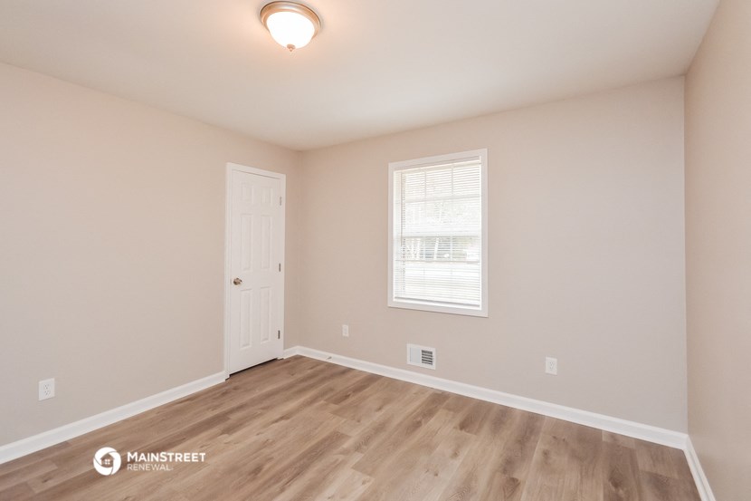the spacious living room with hardwood floors and a white door