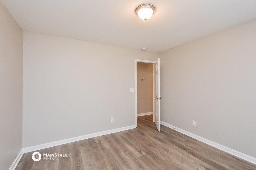 the spacious living room of an apartment with wood flooring and white walls