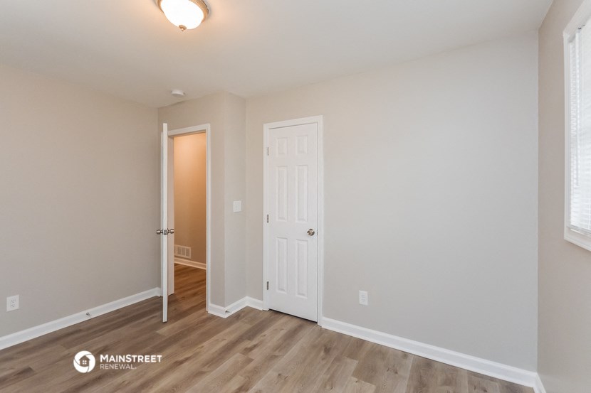 the spacious living room with hardwood floors and a white door