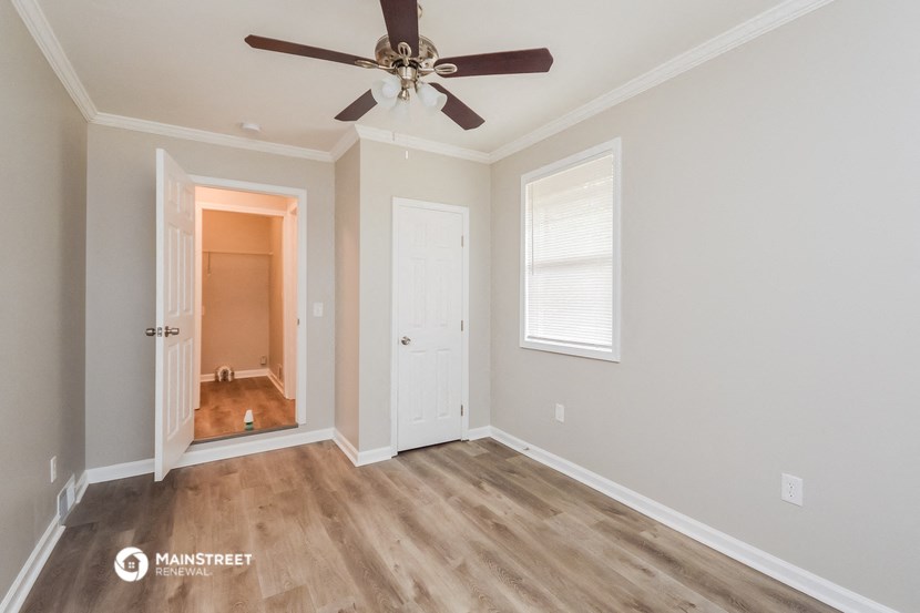 a bedroom with a ceiling fan and a door to a hallway