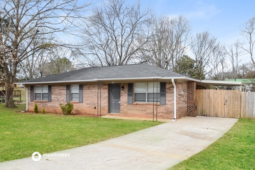 a small brick house with a yard and a wooden fence