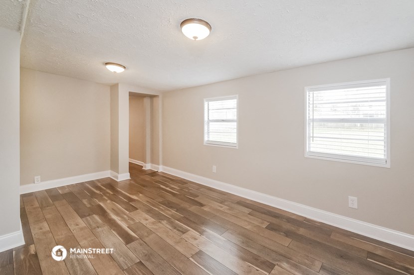 the spacious living room with hardwood flooring and two windows
