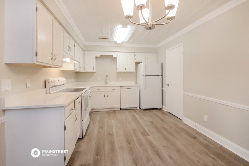 a kitchen with white cabinets and white appliances and wood flooring