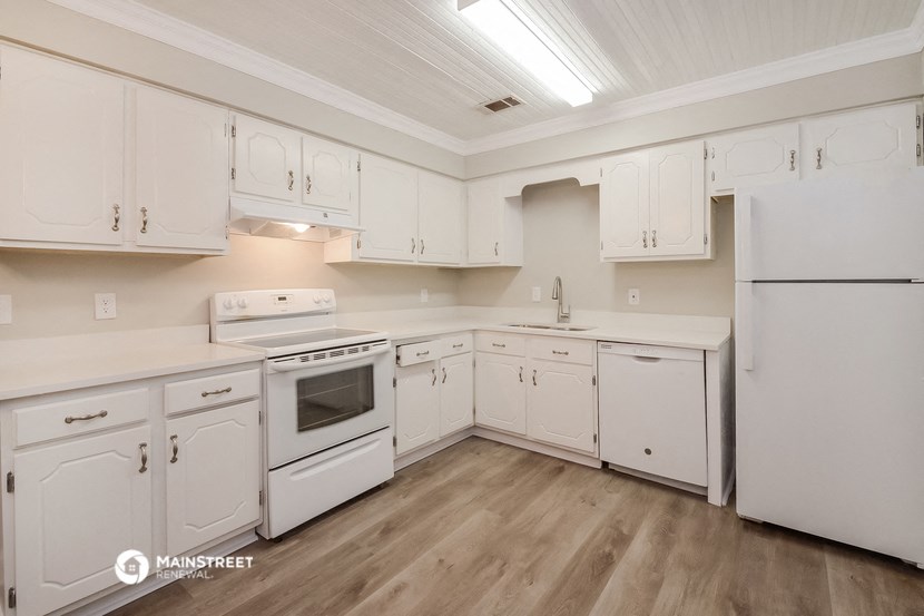 a kitchen with white cabinets and white appliances and wood floors