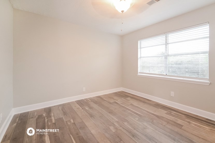 the spacious living room with wood flooring and a large window