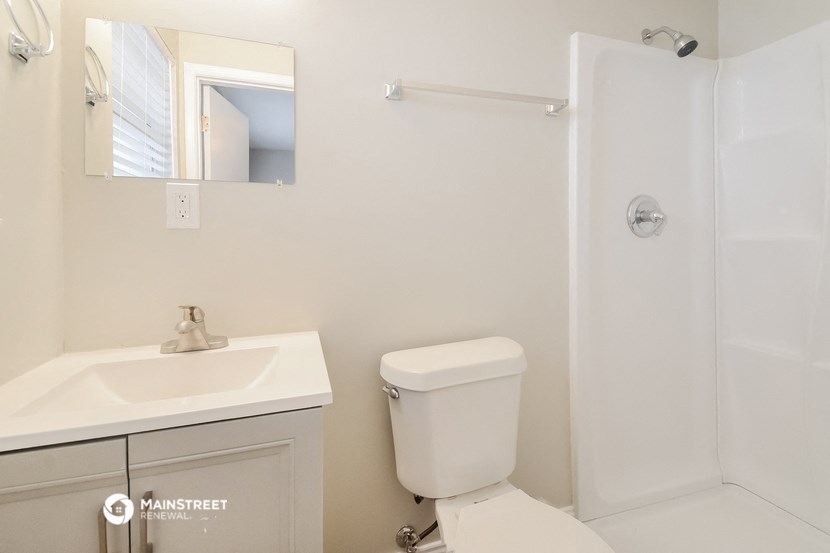 a bathroom with a toilet sink and mirror and a shower