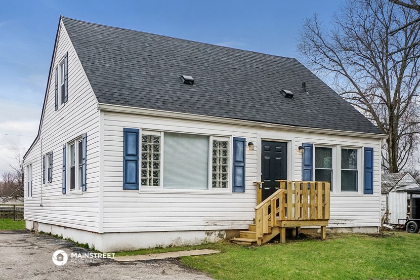 the front of a white house with blue shutters and a deck