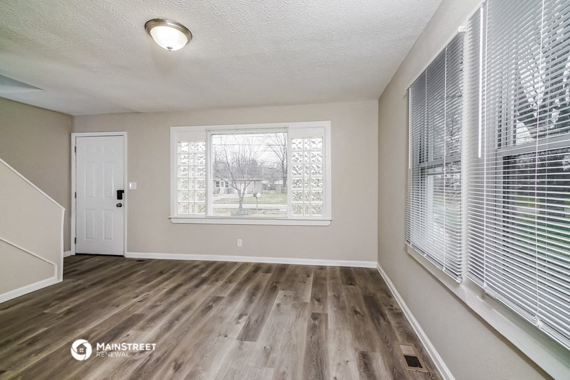 the spacious living room with a large window and wood flooring