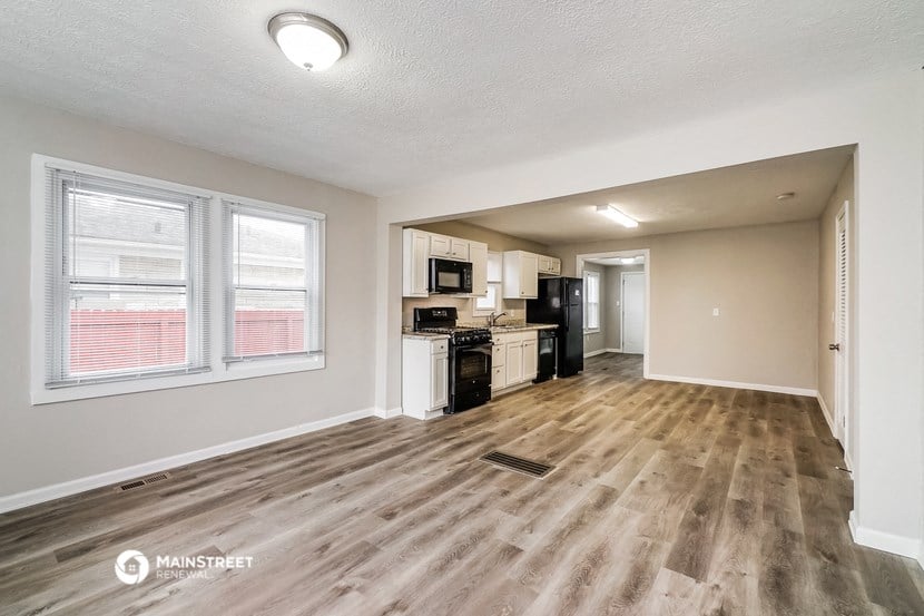the living room and kitchen of an apartment with wood flooring
