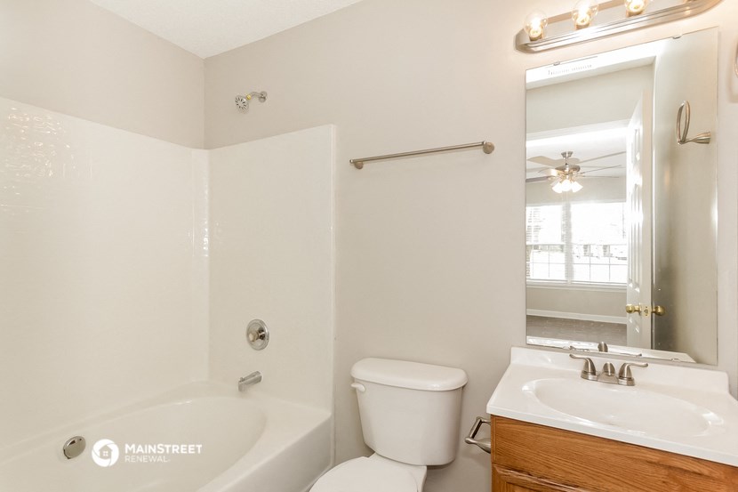 a bathroom with a toilet sink and tub and a mirror