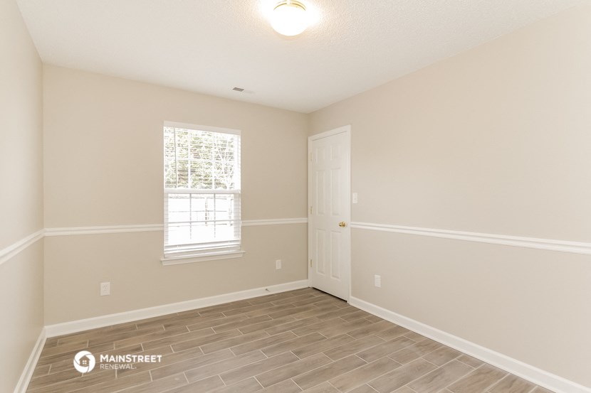 the spacious living room with hardwood flooring and a window