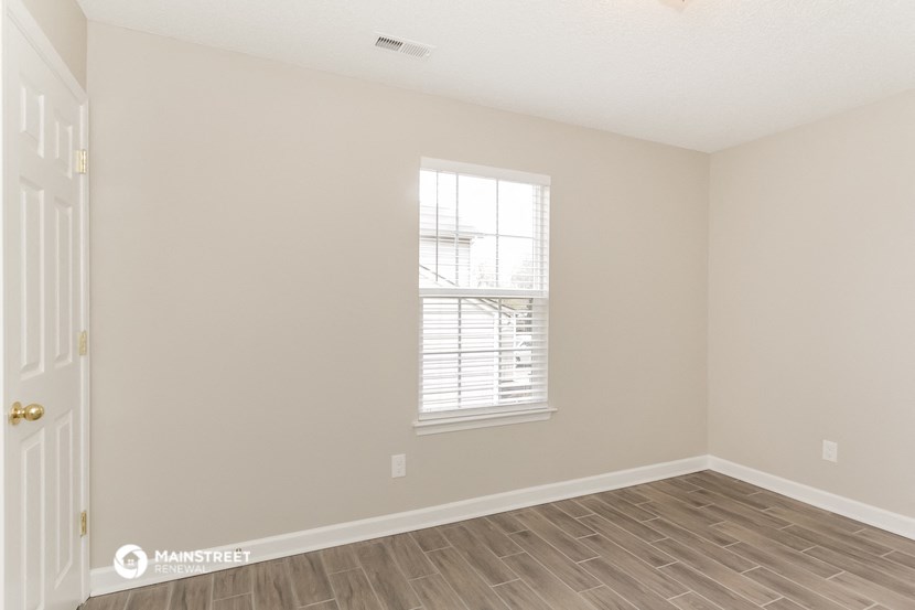 the spacious living room with wood flooring and a window