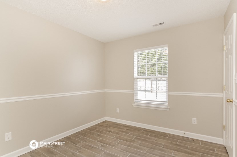 an empty room with a window and a wooden floor