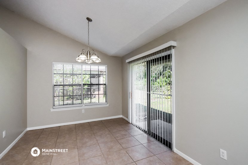 an empty living room with a large window and a door to a patio