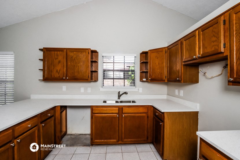 a kitchen with wooden cabinets and white counter tops and a sink