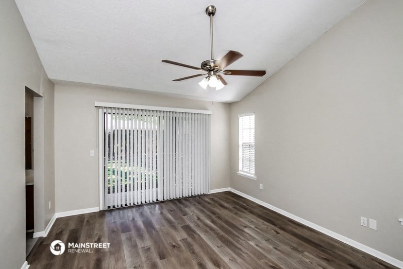 the spacious living room with wood flooring and a ceiling fan