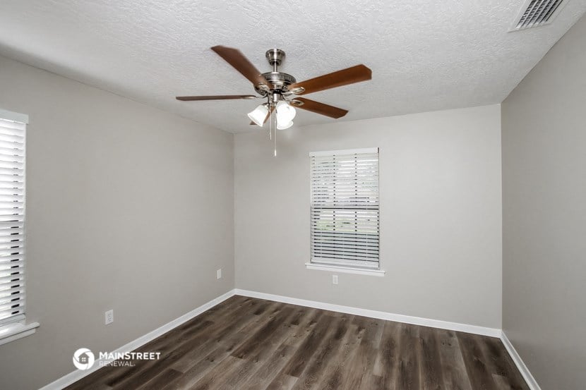 the spacious living room with ceiling fan and wood flooring