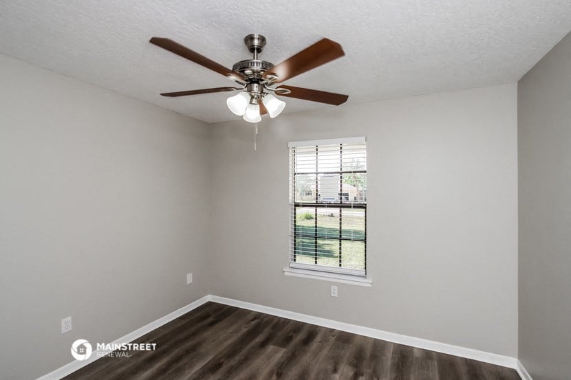 the spacious living room with ceiling fan and window