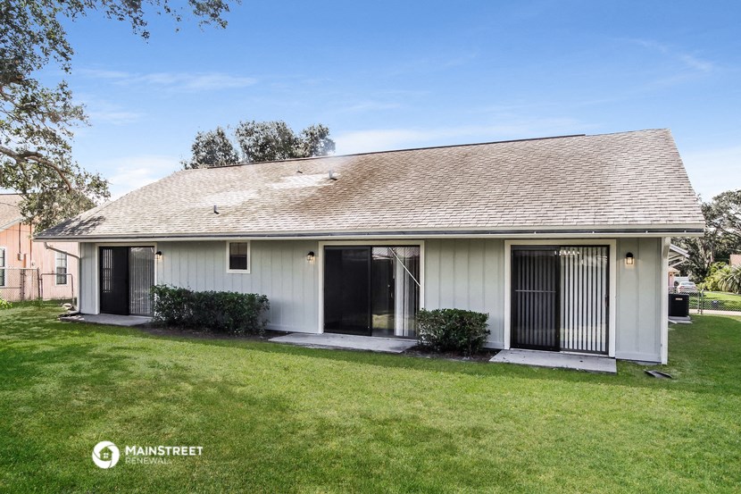 a small white house with two doors and a lawn