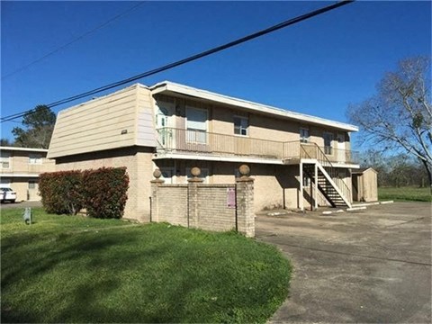 A beige building with a green lawn in front.