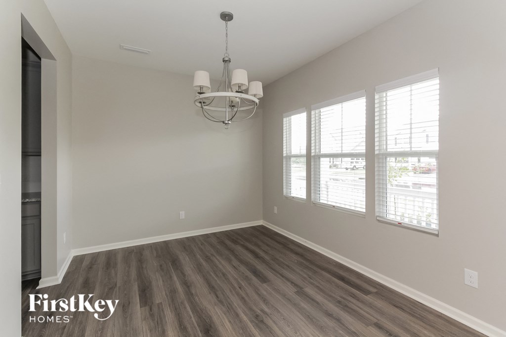 an empty living room with wood floors and a chandelier