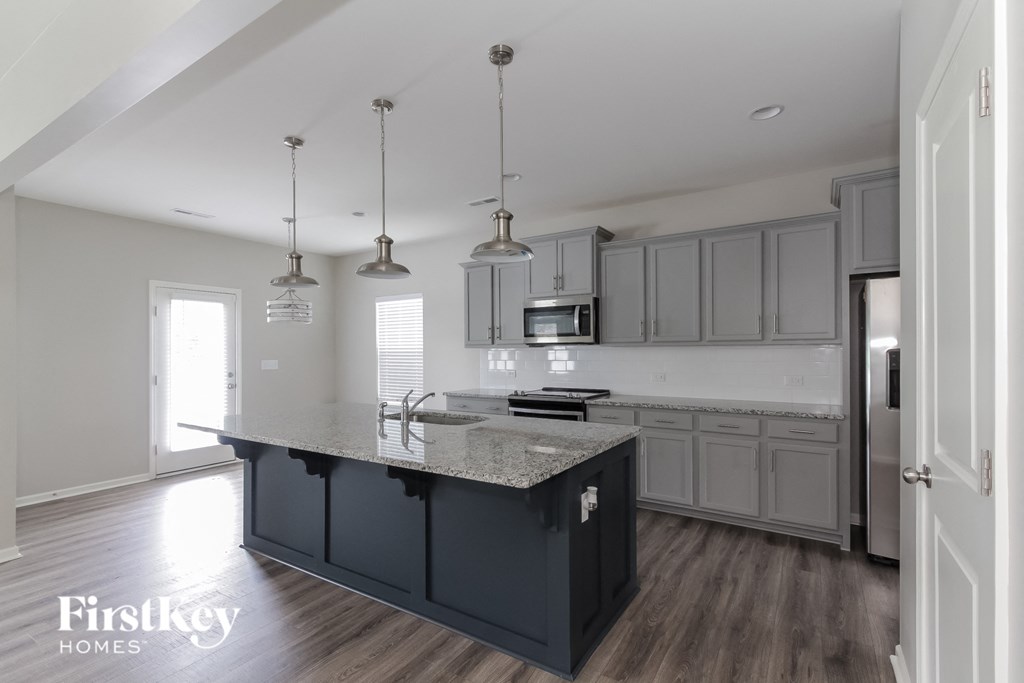 a kitchen with gray cabinets and a marble counter top