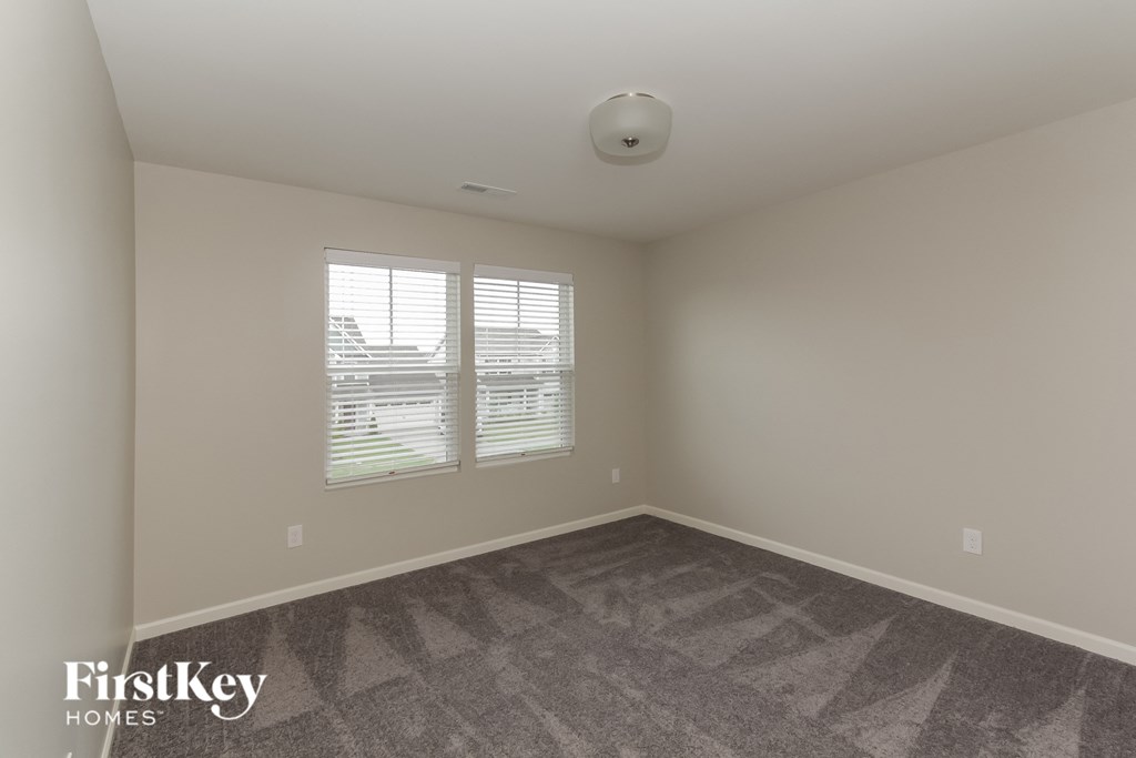 a bedroom with a carpeted floor and two windows