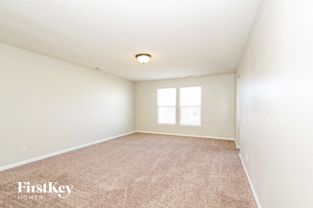 a spacious living room with carpet and a window