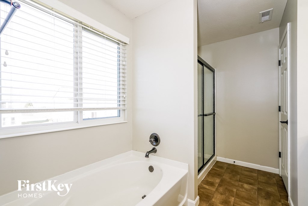 a bathroom with a tub and a shower and a window