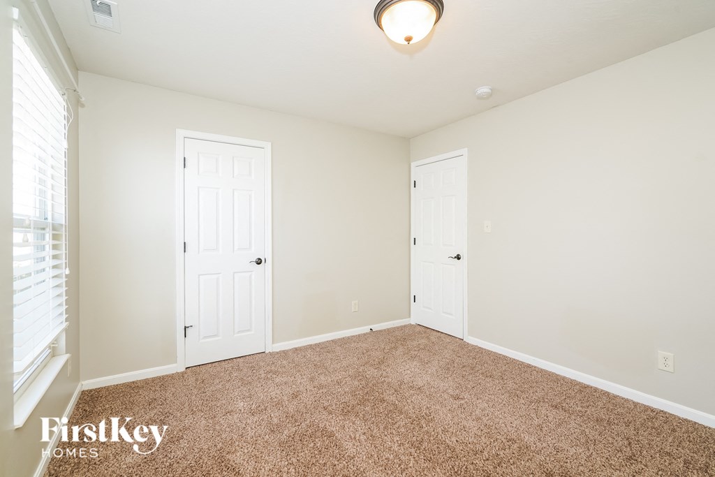 a bedroom with two doors and a carpeted floor
