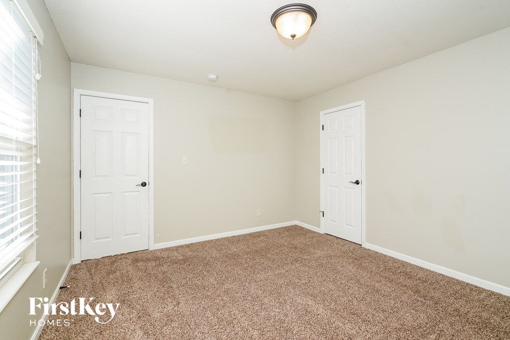 a bedroom with two doors and a carpeted floor