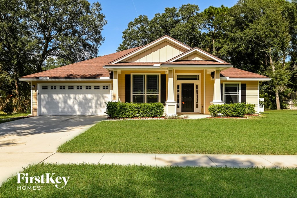 a small yellow house with a lawn and a driveway