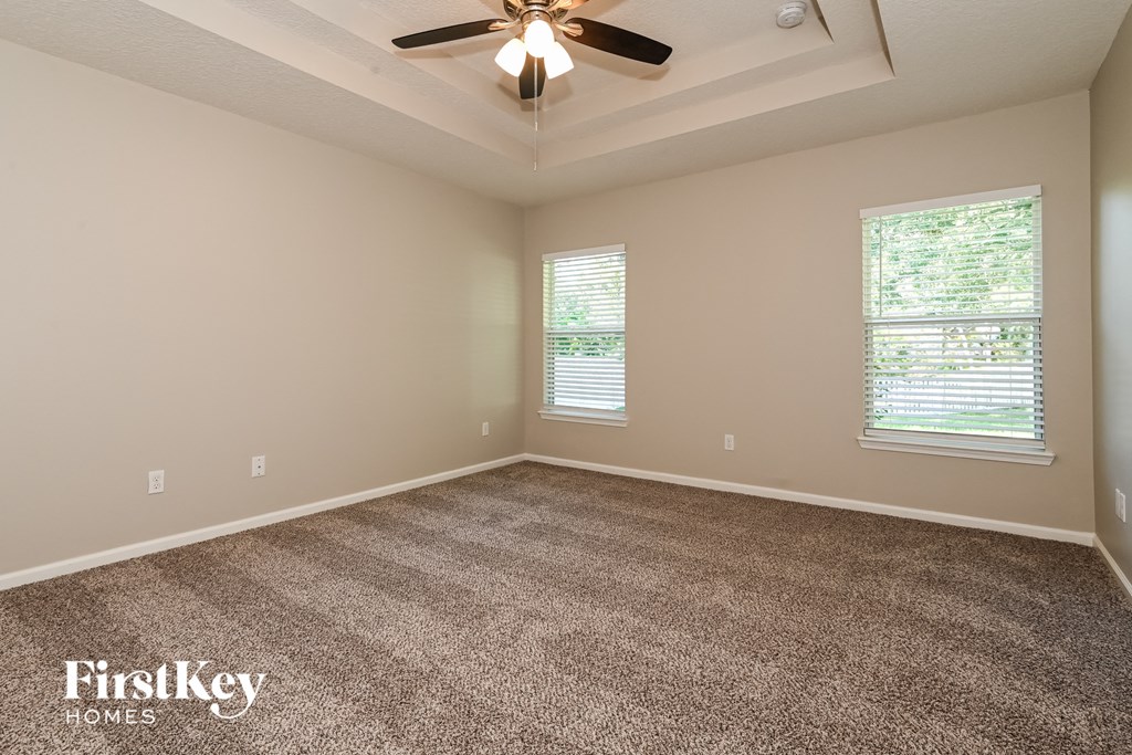 an empty living room with carpet and a ceiling fan