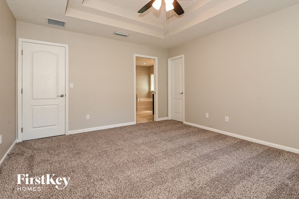 a empty living room with carpet and a ceiling fan
