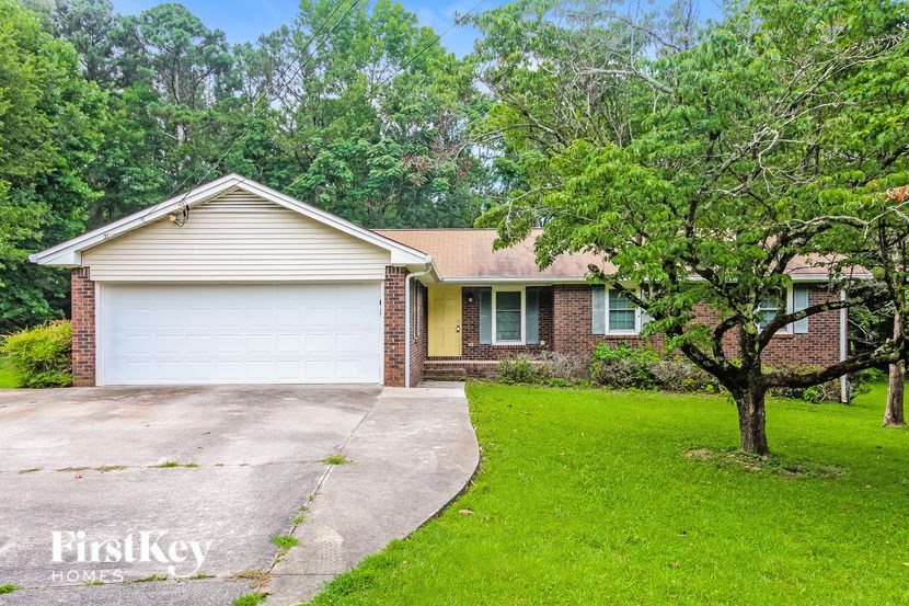 A house with a garage and a tree in front of it.