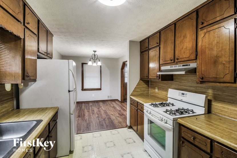 A kitchen with wooden cabinets and a white stove top oven.